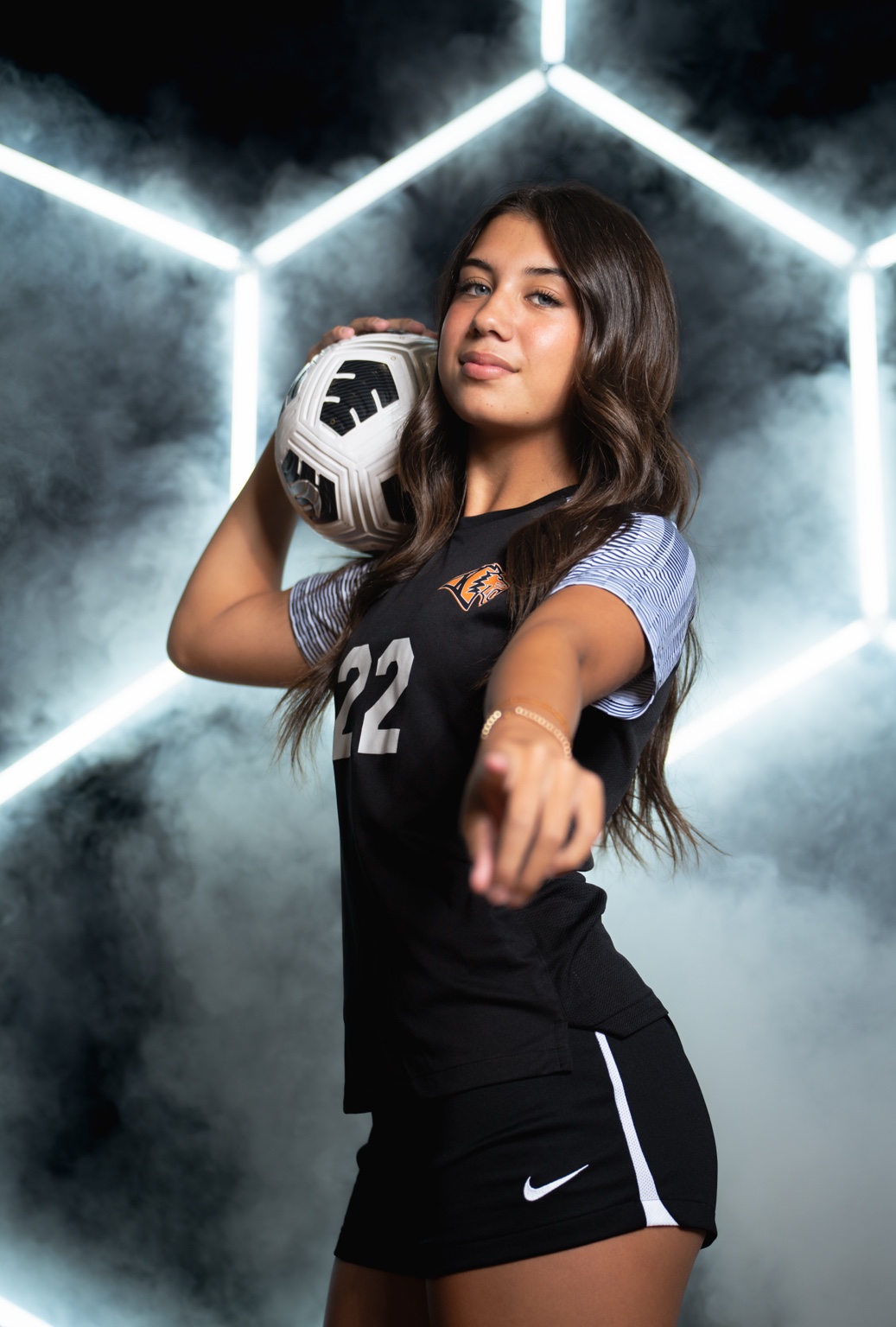 Soccer athlete holding a ball in a smoke-lit portrait